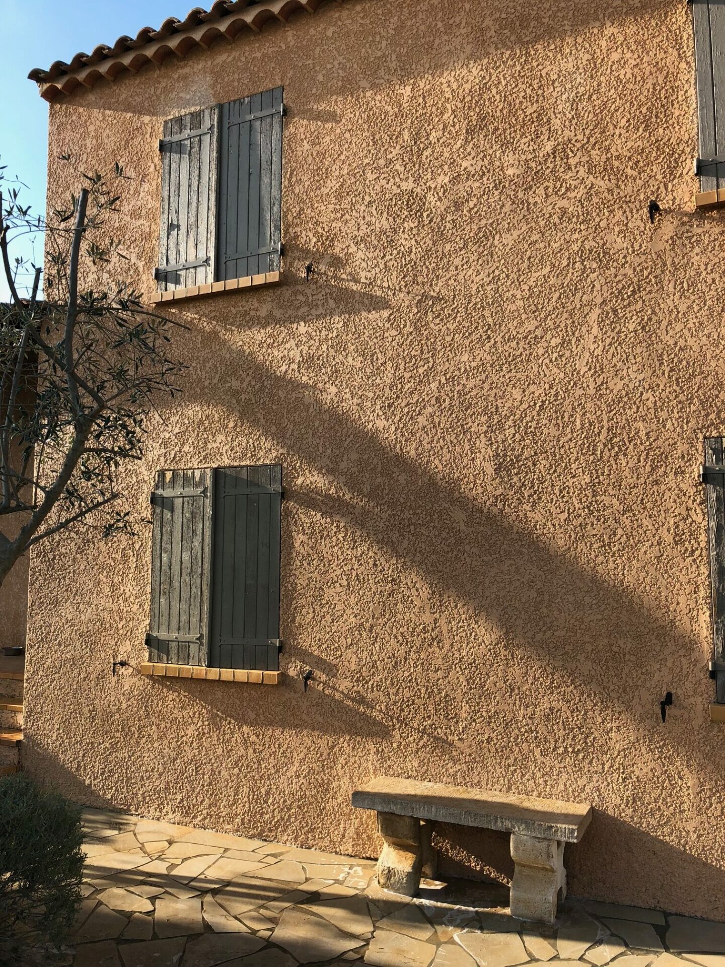 Façade en enduit taloché nettoyée avec dallage en pierre au pied du mur