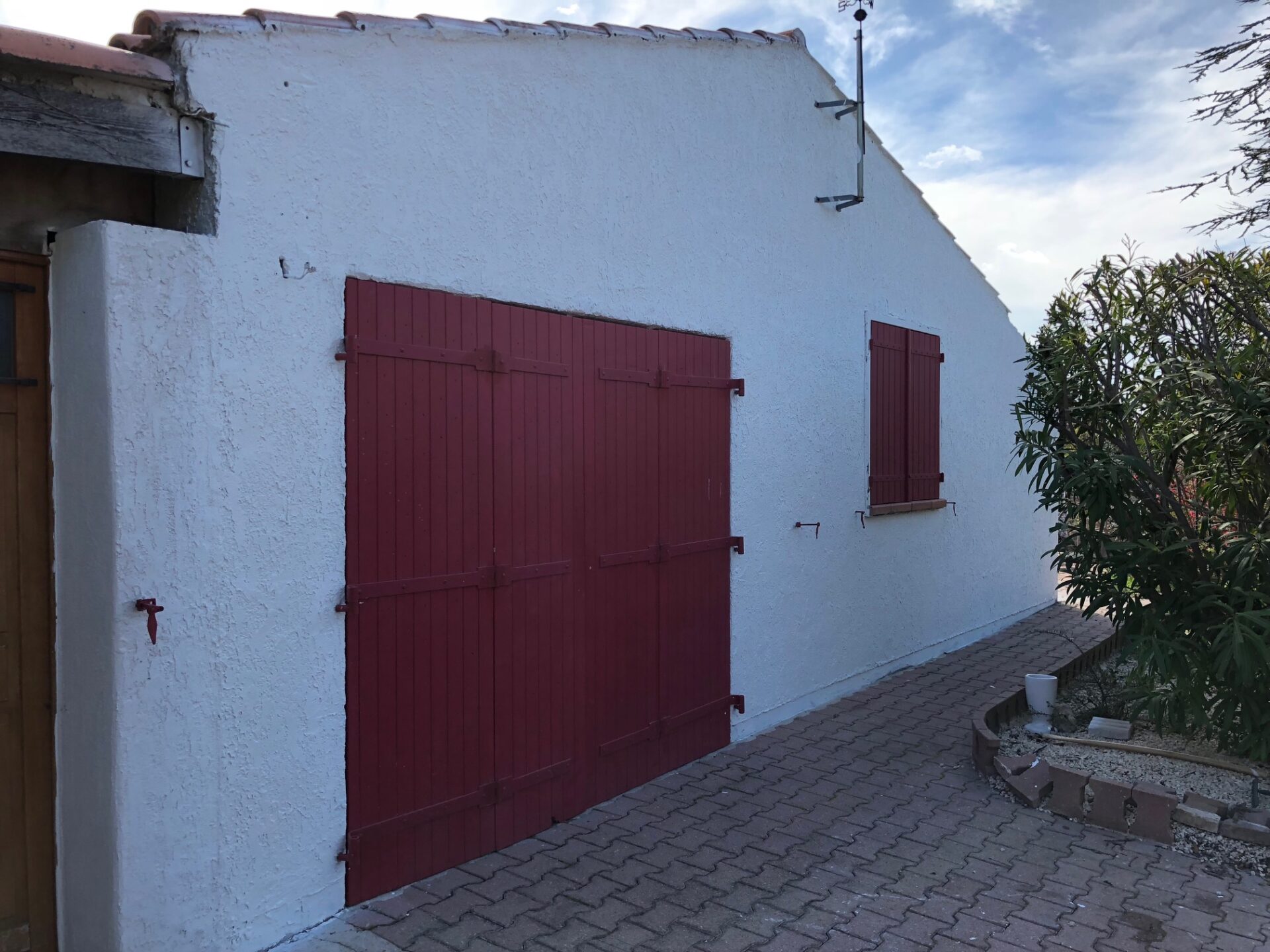 Façade repeinte en blanc avec portes de garage bordeaux