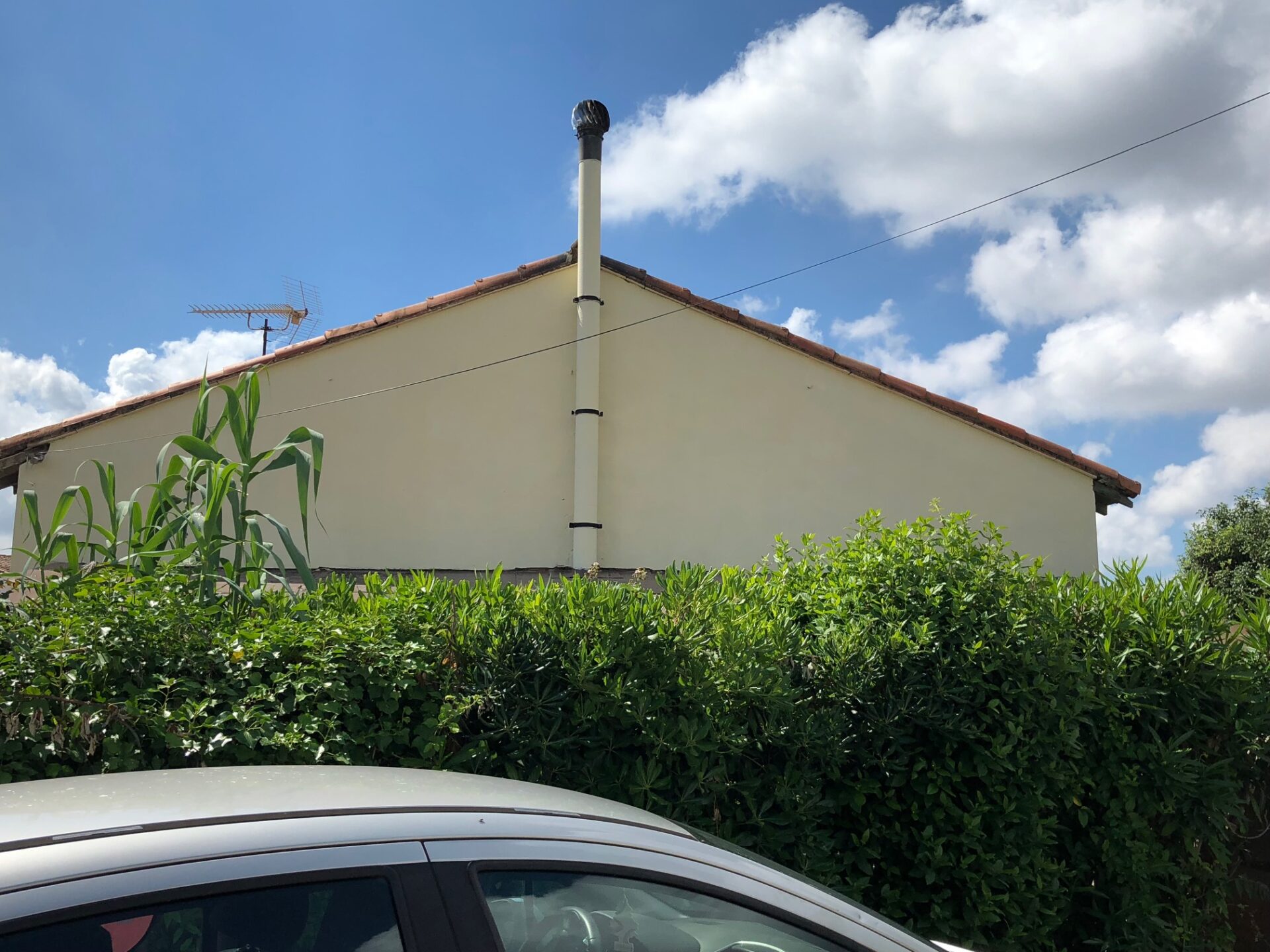 Pignon de maison repeint en ton crème sous une toiture en tuiles