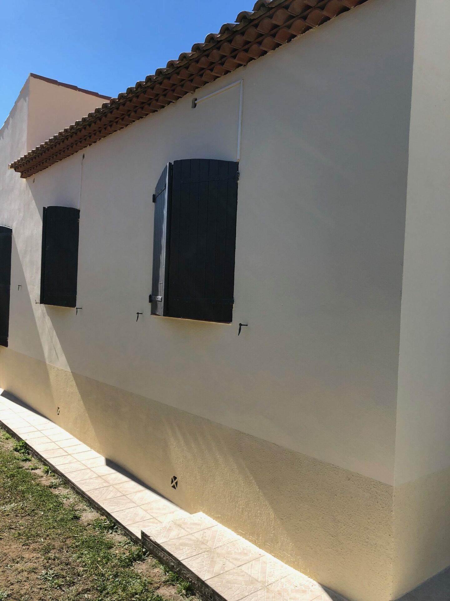 Façade repeinte en ton clair avec volets bois foncés