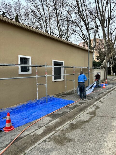 Artisan sur échafaudage appliquant un enduit projeté sur une façade